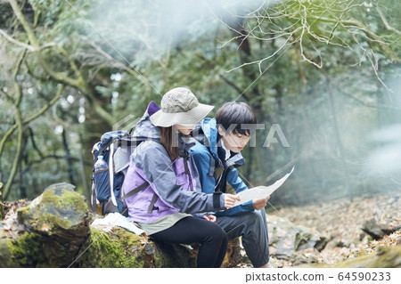 Couple looking at a map while climbing 64590233