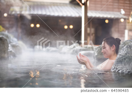 A woman enjoying an open-air bath A woman enjoying an open-air bath 64590485