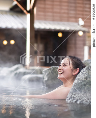 A woman enjoying an open-air bath 64590686