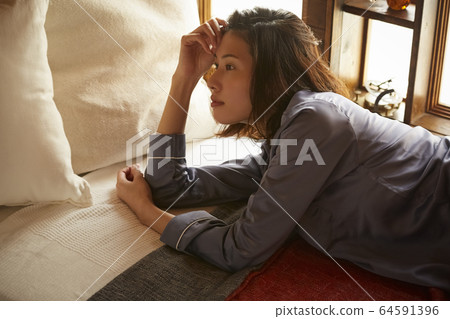 A woman relaxing in the bedroom 64591396