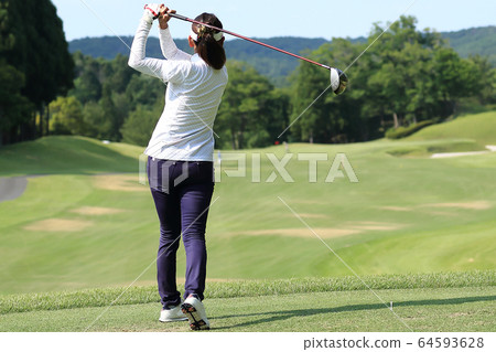 Woman hitting the tee shot Woman hitting the tee shot 64593628