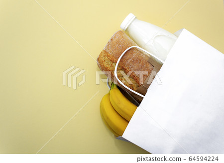 Donation food. Corn, buckwheat, bananas, milk, bread in white bag on yellow background. Donation food. Corn, buckwheat, bananas, milk, bread in white bag on yellow background. 64594224
