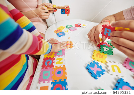 Parents and daughter playing with letter puzzle Parents and daughter playing with letter puzzle 64595321