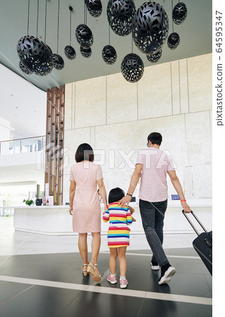 Family walking to hotel reception Family walking to hotel reception 64595347