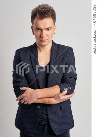 Portrait of serious man in jeans, t-shirt and fitted jacket over gray background Portrait of serious man in jeans, t-shirt and fitted jacket over gray background 64595359