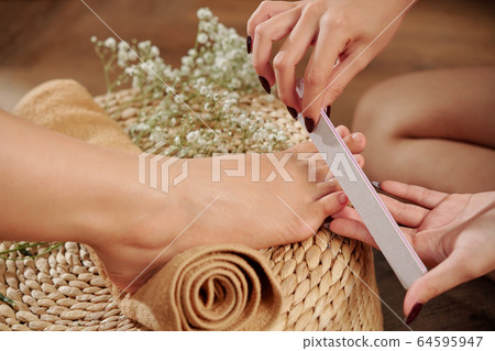 Pedicurist filing toenail 64595947