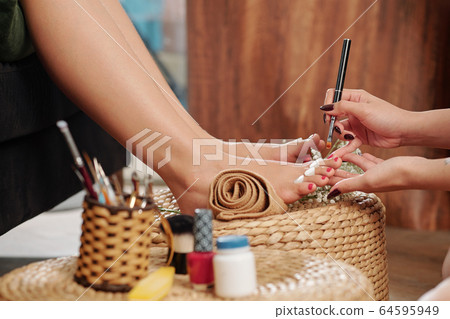 Pedicurist applying cuticle oil Pedicurist applying cuticle oil 64595949