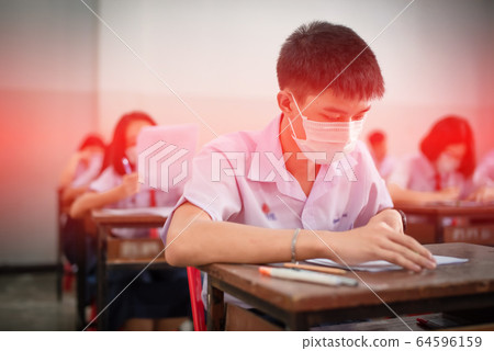 The Asian high school students in a white school uniform wearing the masks to do final exams in the midst of Coronavirus disease 2019 (COVID-19) epidemic and PM 2.5. The Asian high school students in a white school uniform wearing the masks to do final exams in the midst of Coronavirus disease 2019 (COVID-19) epidemic and PM 2.5. 64596159