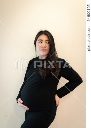 Pretty young pregnant woman standing by the window in room.Concepts of pregnancy and family Pretty young pregnant woman standing by the window in room.Concepts of pregnancy and family 64600105