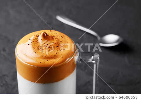 Dalgona Coffee in a transparent cup at black slate. Dalgona Frothy Coffee is a popular Korean drink Dalgona Coffee in a transparent cup at black slate. Dalgona Frothy Coffee is a popular Korean drink 64600555