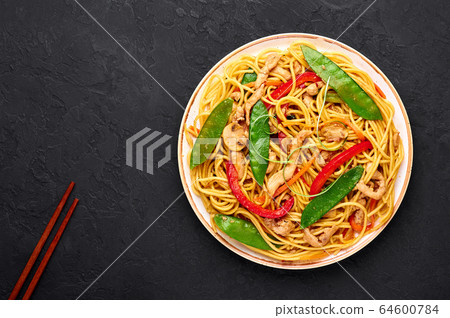 Chicken Lo Mein Noodles in white plate at dark slate backdrop Chicken Lo Mein Noodles in white plate at dark slate backdrop 64600784
