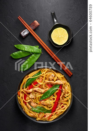 Chicken Lo Mein Noodles in black bowl at dark slate backdrop 64600789