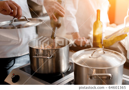 Closeup hands of chef pouring wine into pot with Closeup hands of chef pouring wine into pot with 64601365