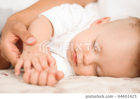 Sweet baby boy sleeping in bed with his mother Sweet baby boy sleeping in bed with his mother 64601425