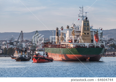 Maneuvers of a huge bulk carrier and tug boats 64604744