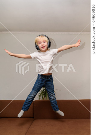 Teen boy listening to music on headphones and 64609016