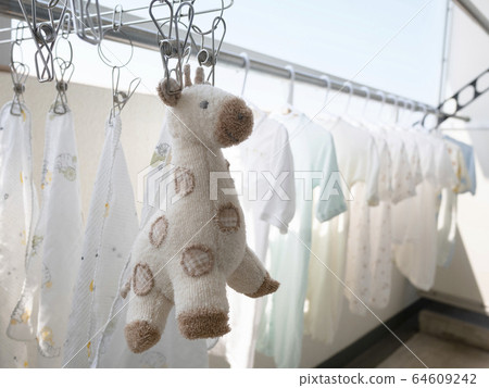 Baby's cute baby clothes on clothesline and stuffed giraffe 64609242