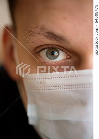 Portrait of a young guy in a protective face mask. New coronavirus (2019-nKoV) infection Portrait of a young guy in a protective face mask. New coronavirus (2019-nKoV) infection 64609479