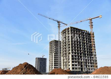 Tower cranes constructing a new residential building at a construction site 64611593