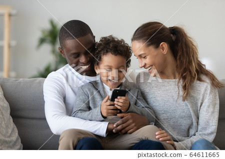 Happy african mixed-race parents with child son laughing using phone 64611665