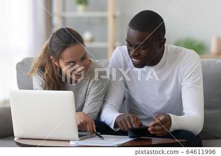 Happy smiling mixed race couple calculating domestic bills at home Happy smiling mixed race couple calculating domestic bills at home 64611996