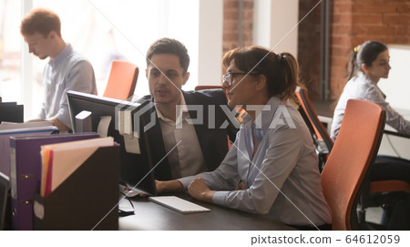 Serious colleagues working together in modern office talking using computer Serious colleagues working together in modern office talking using computer 64612059