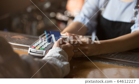 Female customer holding credit card near nfc technology on counter Female customer holding credit card near nfc technology on counter 64612227