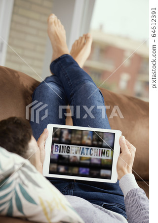man and tablet with the text bingewatching in it 64612391