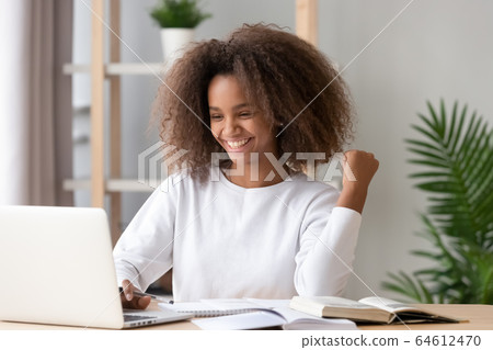 Excited overjoyed african teen girl student winner looking at laptop 64612470