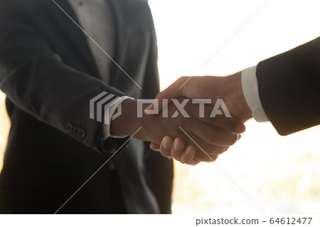 Two diverse african and white businessmen wearing suits shake hands 64612477