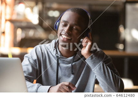 Relaxed young black man wear wireless headphones enjoy good music Relaxed young black man wear wireless headphones enjoy good music 64612480
