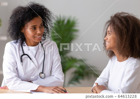 Friendly african american female doctor talking to teen girl patient Friendly african american female doctor talking to teen girl patient 64613228
