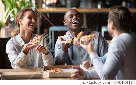 Joyful multicultural friends laughing sharing takeaway pizza meal together 64613418