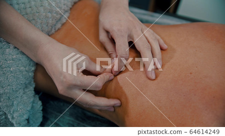 Massage treatment - massage master massaging womans back - squeeze the skin 64614249