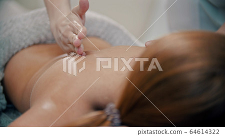 Massage procedure in the cabinet - massage master massaging womans back using massaging oil Massage procedure in the cabinet - massage master massaging womans back using massaging oil 64614322