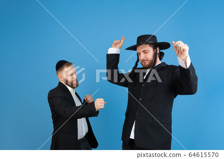 Portrait of a young orthodox jewish men isolated on blue studio background, meeting the Passover 64615570
