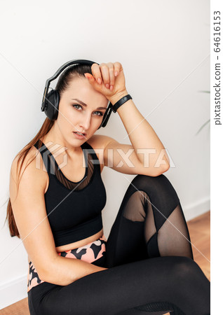 Sporty woman with headphones tired after workout 64616153