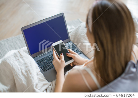 Woman with laptop and smartphone at home. 64617204