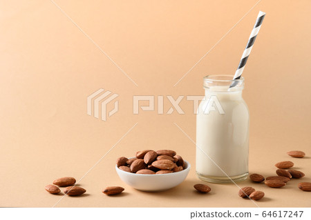 Fresh almond milk in glass bottle on beige. Fresh almond milk in glass bottle on beige. 64617247