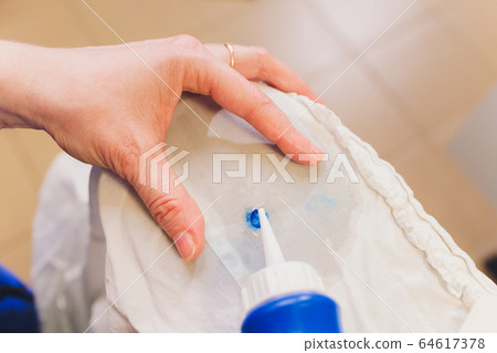 Hand Laundry worker in the process of removing stains by using a special dry-cleaning. 64617378