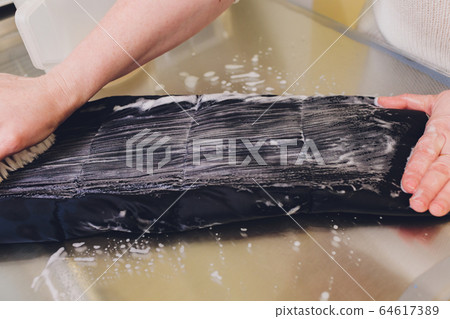 Laundry worker in the process of cleaning fur brush. 64617389