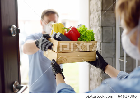 Courier or volunteer delivering shopping to woman Courier or volunteer delivering shopping to woman 64617390