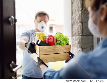 Courier or volunteer delivering shopping to woman Courier or volunteer delivering shopping to woman 64617392