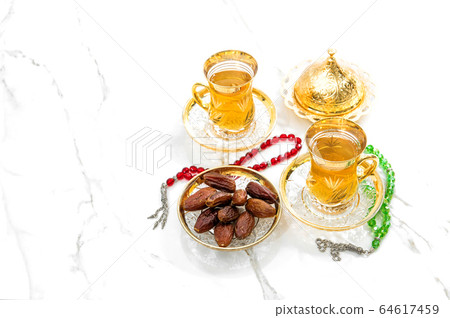 Tea cups dates rosary beads white background Tea cups dates rosary beads white background 64617459
