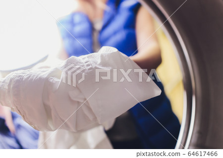 Hands to load the Laundry in the washing machine at the dry cleaners. Hands to load the Laundry in the washing machine at the dry cleaners. 64617466