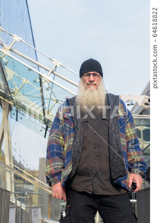 Mature handsome bearded hipster man with eyeglasses in the city Mature handsome bearded hipster man with eyeglasses in the city 64618822