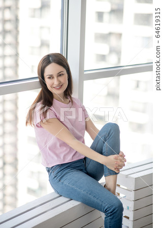 Young happy woman sitting on the windowsill. 64619315