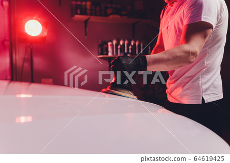 Car detailing - Man with orbital polisher in repair shop polishing car. Selective focus. 64619425