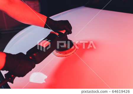 Car detailing - Man with orbital polisher in repair shop polishing car. Selective focus. 64619426