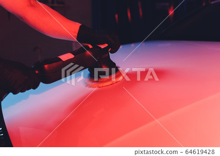 Car detailing - Man with orbital polisher in repair shop polishing car. Selective focus. Car detailing - Man with orbital polisher in repair shop polishing car. Selective focus. 64619428